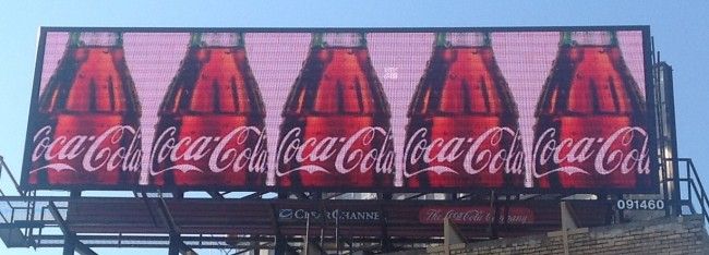 A billboard advertising Coca Cola with six repeated images of a coke bottle.