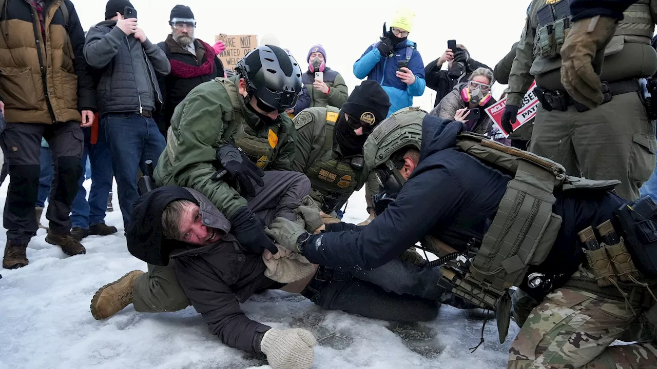 A man being held down in the snow by USA ICE agents