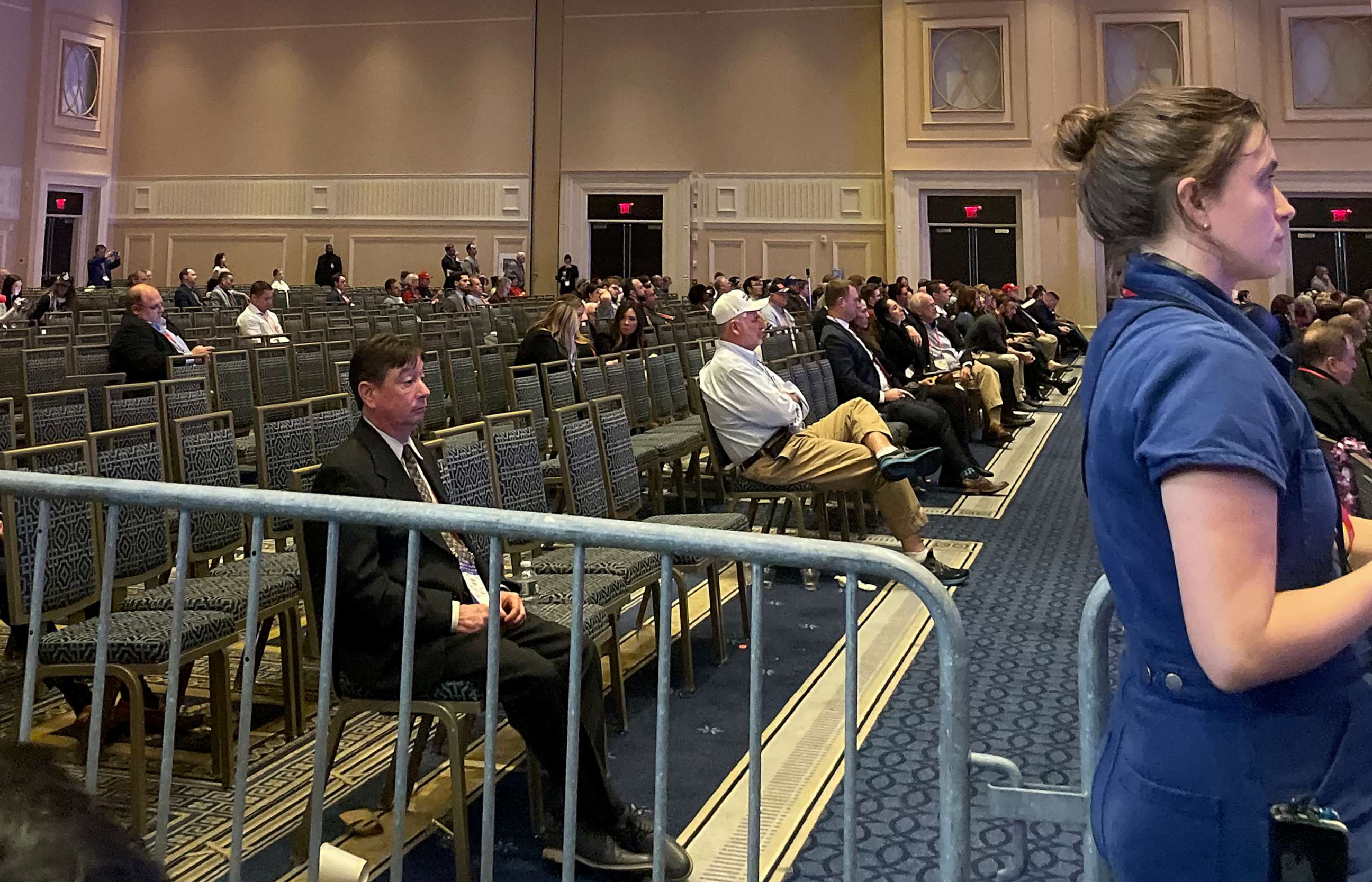 the back rows of a conference room, where the chairs are mostly empty